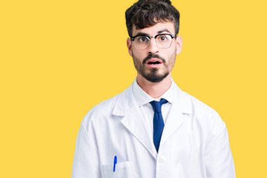 Korkuyor ve şok sürpriz ifade, korku ve heyecan yüz ile izole arka plan üzerinde beyaz önlük giyen genç profesyonel bilim adamı.