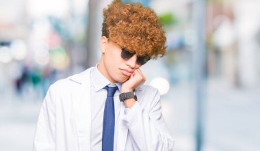 Profesyonel ceket ve yorgun ve bıkkın ile depresyon sorun Çapraz kollar ile seyir düşünüyorum güneş gözlüğü takan genç yakışıklı bilim adamı.