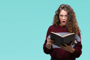 Genç esmer kız izole arka şok sürpriz yüzü, korkuyor ve korku ifadesi ile heyecanlı olan korkmuş üzerinde gözlük takan bir kitap okuma