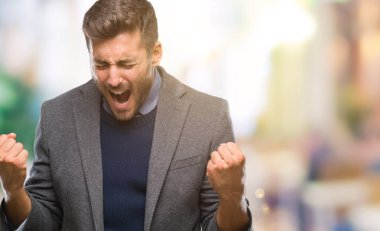 Gülümseyen ve başarı için çığlık genç yakışıklı iş adamı izole arka plan çok mutlu ve heyecanlı kaldırdı, silah ile kazanan jest yapıyor üzerinde. Kutlama kavramı.