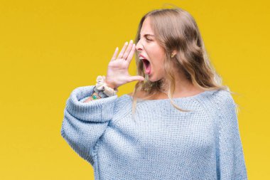 Bağırarak ve ağzı üzerinde el ile yan için çığlık izole arka plan üzerinde kış kazak giyen güzel genç sarışın kadın. İletişim kavramı.