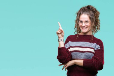 Kameraya bakarak yan el ve parmak ile işaret yüzünde kocaman bir gülümseme ile izole arka plan üzerinde gözlük güzel esmer kıvırcık saçlı Genç kız.