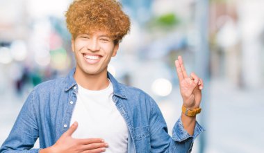 Afro saçlı kot giyen genç yakışıklı adam ceket Swearing göğüs ve parmaklar, el ile bir sadakat sözü yemin yapma