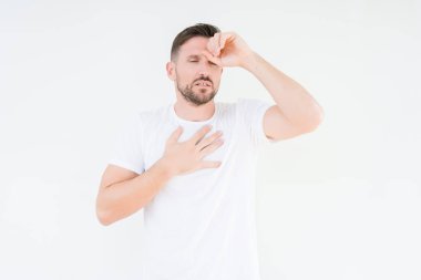 Genç yakışıklı adam giyiyor rahat beyaz t-shirt izole arka plan dokunmadan üzerinde hastalık ve ateş, grip ve soğuk, virüs hasta için alın