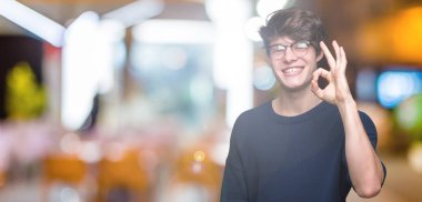 İzole arka plan el ve parmaklar ok işaretiyle yapıyor olumlu gülümseyen üzerinde gözlük takan yakışıklı delikanlı. Başarılı ifade.