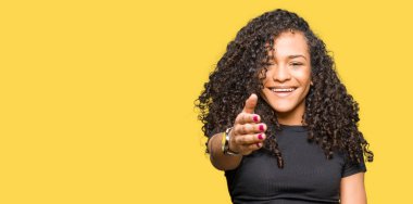 Tebrik ve konuksever dost sunan karşılıklı gülümseyen kıvırcık saçlı Genç güzel kadın. Başarılı iş.