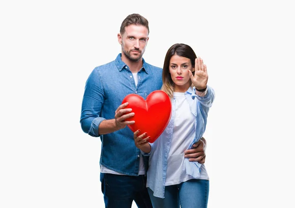 恋爱中的年轻夫妇用张开的手在孤立的背景上拿着红心做停止标志 用严肃而自信的表情 防守姿态 — 图库照片