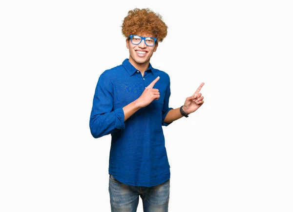アフロ髪青い眼鏡笑顔で側に つの手と指で指しているカメラを見て若いハンサムな男 — ストック写真