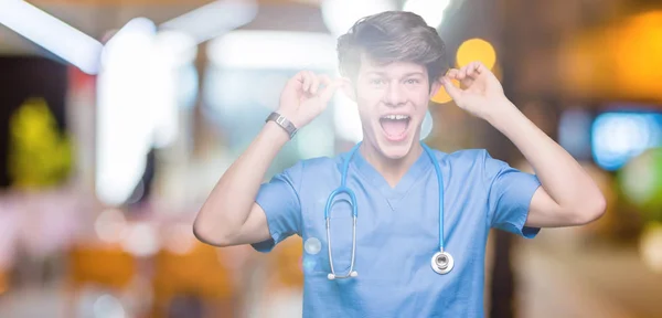 Junge Ärztin Arztuniform Vor Isoliertem Hintergrund Lächelnd Die Ohren Mit — Stockfoto