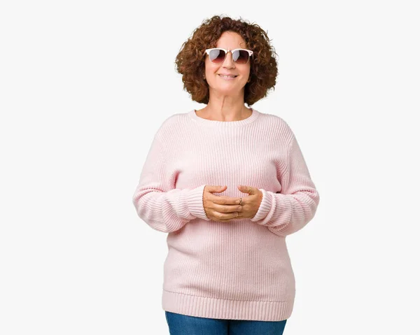 美しい中間エイガー年配の女性にピンクのセーター サングラスを着用が一緒に背景手を分離し リラックスして 陽気な笑顔を祈る 成功と楽観的な — ストック写真