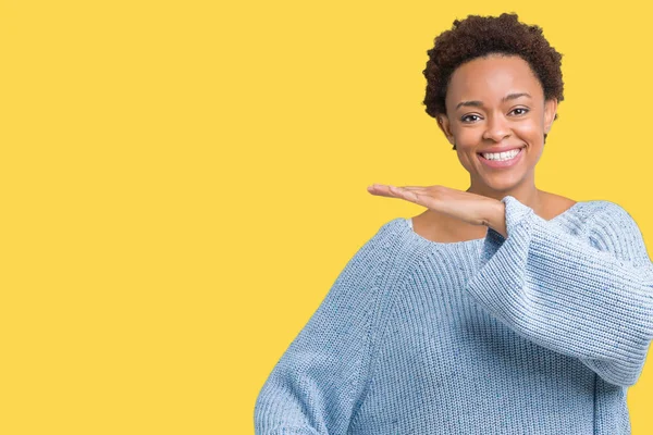 İle büyük ve büyük boy işaret, ölçü birimi sembol gösteren el eller izole arka plan üzerinde bir kazak giyen genç güzel Afrikalı-Amerikalı kadın. Kameraya bakarak gülümsüyordu. Ölçüm kavramı.