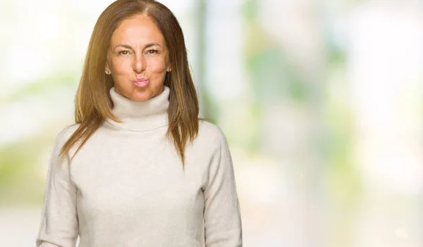 美しい中年成人女性が変な顔で頬に息を切らし孤立の背景に冬のセーターを着ています クレイジー式空気で膨らませ口 — ストック写真