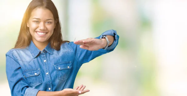 孤立した背景ジェスチャーで示す大きな手と大きなサイズ記号メジャー シンボル上ブルーデニム シャツを着た若い美しいブルネット女性 カメラを見て笑っています 測定概念 — ストック写真