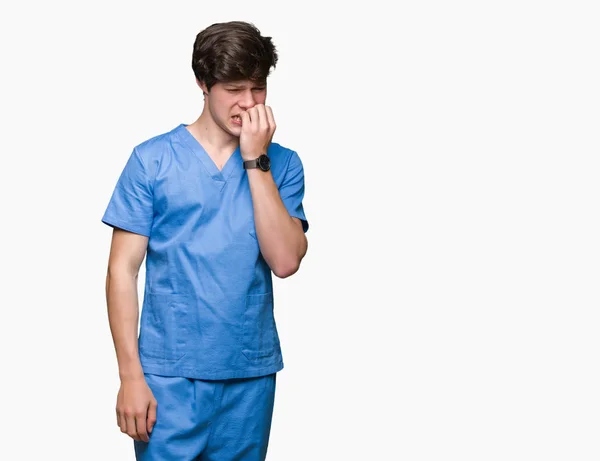 年轻的医生穿着医疗制服在孤立的背景看起来紧张和紧张的手在嘴咬指甲 焦虑问题 — 图库照片