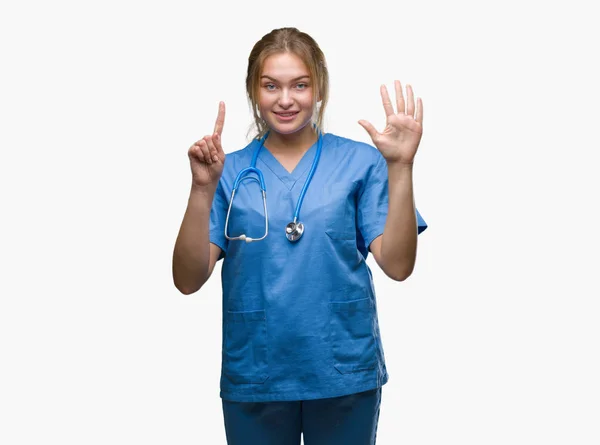 年轻的高加索医生妇女穿着外科医生制服在孤立的背景显示和指向用手指数字六 同时微笑着自信和快乐 — 图库照片