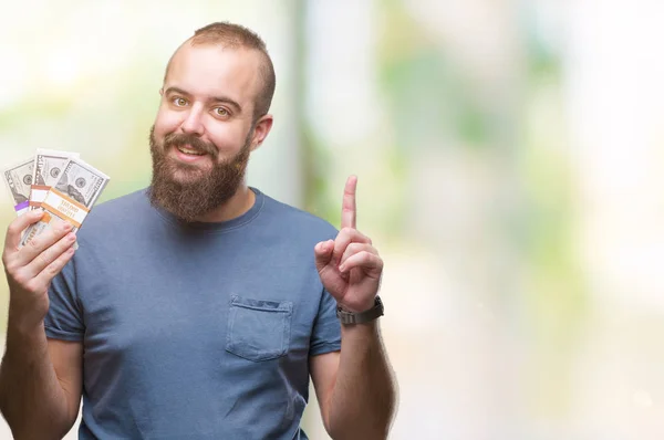 Jovem Hipster Homem Segurando Monte Dinheiro Sobre Fundo Isolado Surpreendido — Fotografia de Stock