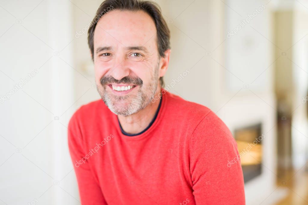 Handsome middle age man smiling looking at the camera at home