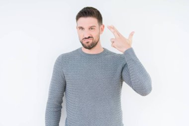 Casual kazak izole üzerinde giyen genç yakışıklı adam arka plan çekim ve öldürmek kendini işaret eden el ve baş parmak, intihar jest.