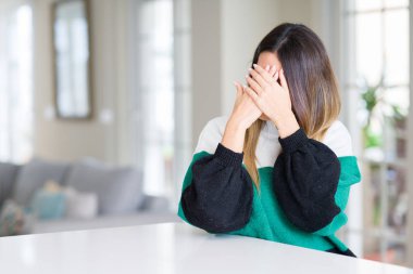 Yüzünü elleriyle ağlayarak süre kapsayan üzgün ifade ile kış kazak evde giyen genç güzel kadın. Depresyon kavramı.