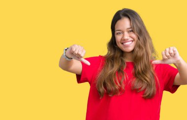 Yüzünde gülümseme ile kendinden emin görünüyorsun, kendini gururlu ve mutlu parmakları ile işaret izole arka plan üzerinde kırmızı t-shirt giyen genç güzel esmer kadın.