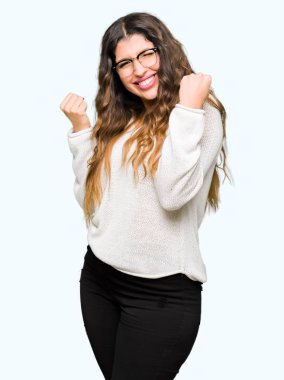 Genç güzel kadın kutluyor gözlük takan şaşırttı ve başarı için kaldırdı kollarını açarak hayrete ve gözleri açık. Kazanan kavramı.