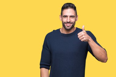 Hareketi el ile mutlu yaşasın yapıyor izole arka plan üzerinde kazak giyen genç yakışıklı adam. Başarı gösteren kameraya bakarak ifade onaylama.