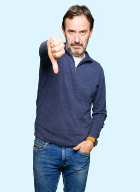Orta yaş yakışıklı adam mutsuz ve kızgın ret gösterilen ve başparmak aşağı hareketi ile negatif seyir bir kazak giyiyor. Kötü ifade.