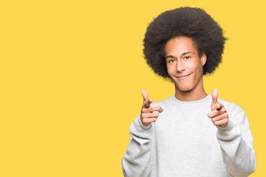 Afrikalı-Amerikalı genç afro saçlı sportif kazak işaret parmak kamera ile mutlu ve komik yüz için giyiyor. İyi enerji ve vibes.