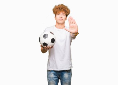 Açık eliyle dur işareti ile ciddi ve kendine güvenen ifade, savunma jest yapıyor futbol futbol topu tutan genç yakışıklı adam