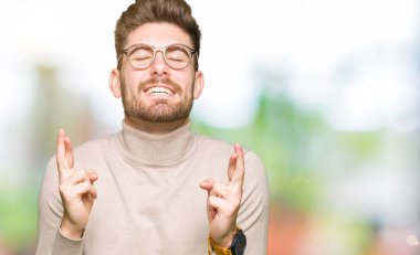 Umut ve gözleri kapalı geçiş parmaklarıyla gülümseyen gözlüklü genç yakışıklı iş adamı. Şans ve batıl kavramı.