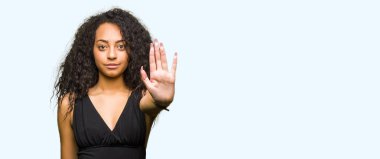 Kıvırcık saçlı giyen moda etek stop yapmak ile genç güzel kız elin avuç ile şarkı. Negatif ve ciddi bir jest yüz ifadesiyle uyarı.