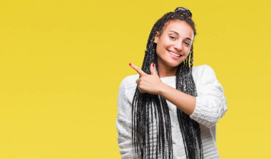 Genç izole arka neşeli bir gülümseme ile el ve parmak kadar kameraya bakarak yüzündeki mutlu ve doğal ifade ile yan ile işaret yüz üzerinden kazak giyen saç Afro-Amerikan Kız örgülü.