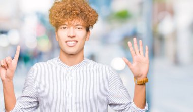 Şık gömlek gösterme ve parmakları ile işaret giyen afro saçlı Genç yakışıklı iş adamı kendinden emin ve mutlu gülümseyerek süre 6 numara.