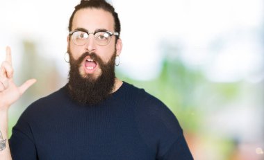 Uzun saç ve sakal başarılı fikirle parmağı yukarıyı gözlüklü genç hipster adam. Çıktıktan ve mutlu. Bir numara.