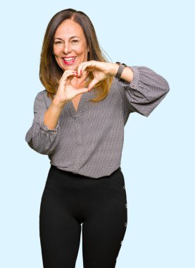 Kalp simgesi ve elleriyle şekil gösterilen aşık gülümseyen güzel orta yaş bir iş kadını. Romantik kavramı.