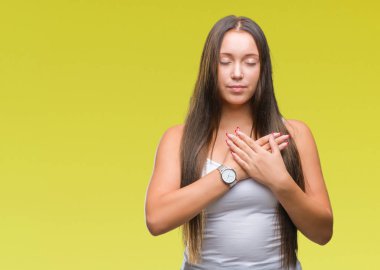 Göğüs kapalı gözler ve yüzünde minnettar jest ile güzel bir beyaz genç kadın ile gülümseyen izole arka plan üzerinde eller. Sağlık kavramı.