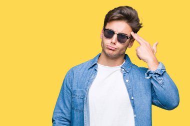 Genç yakışıklı adam giyen güneş gözlüğü izole üzerinde çekim ve öldürmek kendini el ve parmaklara baş, intihar jest işaret arka plan.