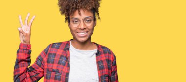 Güzel genç Afro-Amerikan kadın gözlük gösterilen ve parmakları ile işaret izole arka plan üzerinde ise kendinden emin ve mutlu gülümseyerek üçüncüsü.