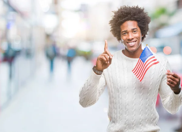 Afro american man flag of United States of America over isolated background surprised with an idea or question pointing finger with happy face, number one