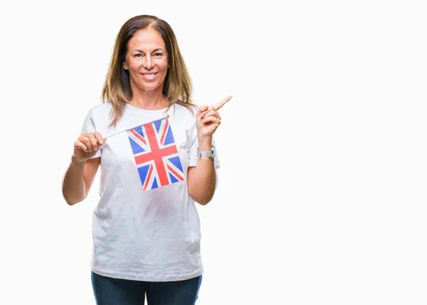 Латиноамериканка Средних Лет Держащая Флаг Великобритании Изолированном Фоне Довольна Указывая — стоковое фото