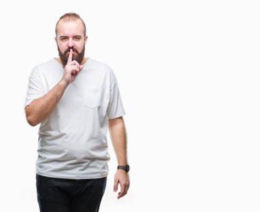 Dudaklarında parmak ile sessiz olmanı izole arka plan üzerinde rahat t-shirt giyen genç beyaz hipster adam. Sessizlik ve gizli kavramı.