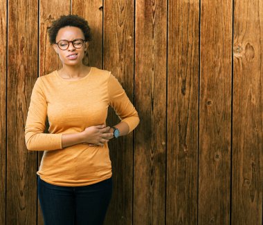 Genç güzel Afrikalı-Amerikalı kadın üzerinde gözlük takan izole mide üzerinde el ile arka plan çünkü hazımsızlık, ağrılı hastalık hasta hissediyor. Ağrısı kavramı.