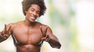 Çıplak vücut zafer işareti yapıyor parmak gösterilen kamera seyir gülümseyen izole arka plan üzerinde gösterilen Afro Amerikalı gömleksiz adam. İki numaralı.