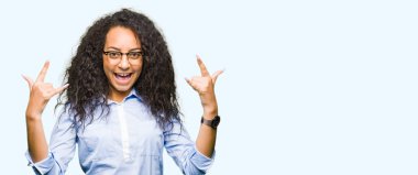 Kıvırcık saçlı deli ifade rock simge elle yapıyor ile bağırarak gözlüklü genç güzel iş kız. Müzik yıldızı. Ağır kavramı.