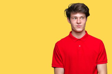 Görünümlü yan ve dik dik bakma uzağa düşünce gülümseyen izole arka plan üzerinde kırmızı t-shirt giyen genç yakışıklı adam.