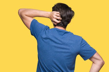 İzole arka plan geriye düşünme hakkında şüphe ile baş taraftan üzerinde mavi t-shirt giyen genç yakışıklı adam
