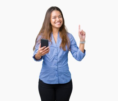 Genç güzel esmer iş kadını Smartphone izole arka bir fikir ya da soru işaret parmağı gülen yüz, bir numara ile sürpriz üzerinde kullanma