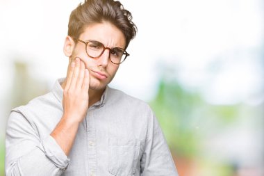 Diş ağrısı veya dişlerde dişlerle ilgili hastalık nedeniyle ağız acı ifadesi ile el ile dokunmak izole arka plan üzerinde gözlük takan yakışıklı delikanlı. Diş hekimi kavramı.