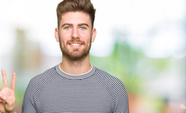 Çizgili süveter gösterme ve parmakları ile işaret giyen genç yakışıklı adam kendinden emin ve mutlu gülümseyerek iken üçüncü.