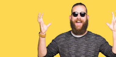 Genç hipster adam deli ve silah ile başarı için hayran kutluyor güneş gözlüğü takıyor kaldırdı ve açık gözleri çığlık heyecanlı. Kazanan kavramı